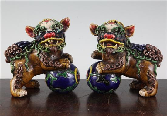 A pair of Chinese polychrome pottery figures of lion-dogs with balls, height 12cm